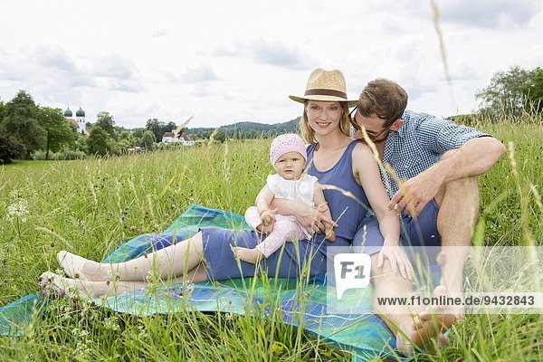 Family sitting on blanket in field  portrait