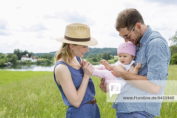 Parents holding baby daughter in field