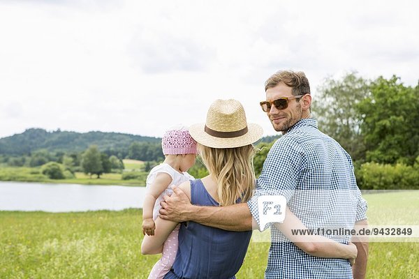 Frau hält Baby-Tochter  Mann schaut über die Schulter