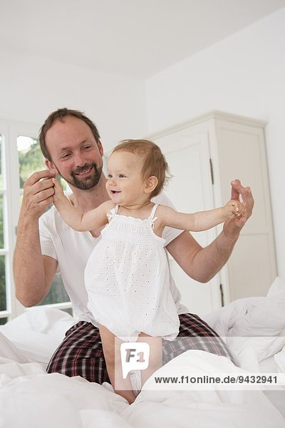 Vater spielt mit der kleinen Tochter im Bett