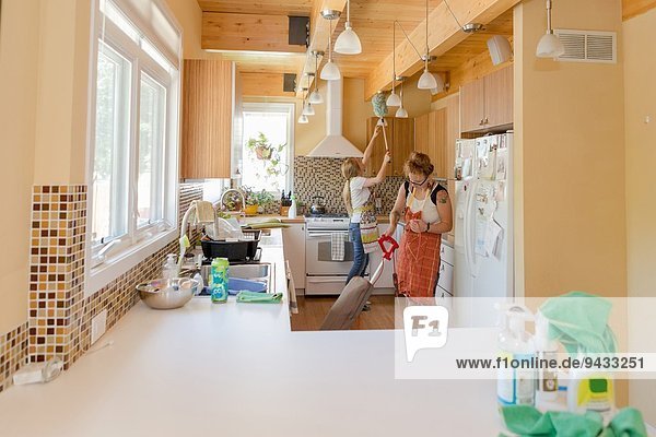 Junge Frauen reinigen Küche mit grünen Reinigungsmitteln