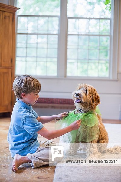 Young boy playing dress up with pet dog