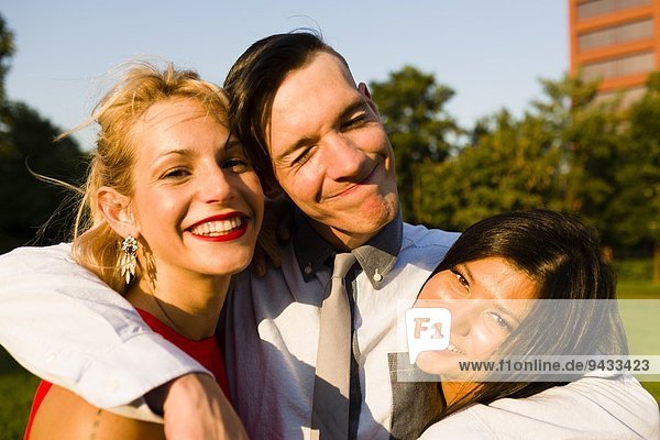 Porträt von drei jungen erwachsenen Freunden beim Umarmen