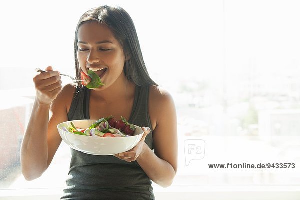 Frau isst Salat zu Hause