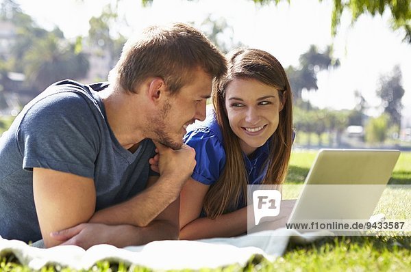 Couple using laptop in park