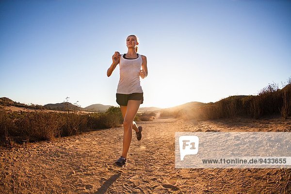 Young woman jogging on sunlit path  Poway  CA  USA