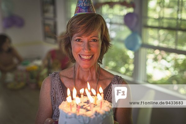Porträt einer reifen Frau mit Geburtstagskuchen und Kerzen