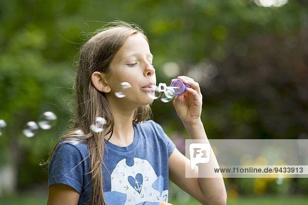 Mädchen bläst Blasen im Garten