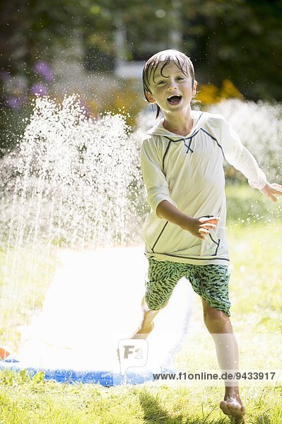 Boy playing with garden sprinkler