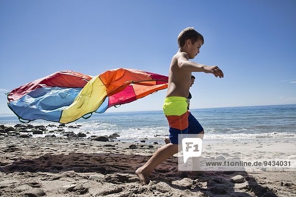 Mother and son running with multi colored textile on beach  County Park  Los Angeles  California  USA