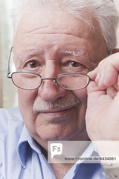 Älterer Mann  der über eine Brille schaut
