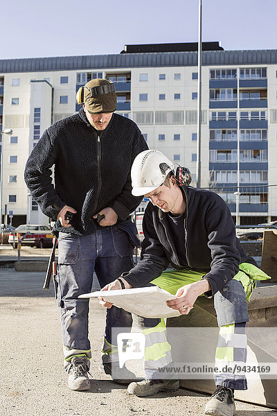 Bauarbeiter analysieren Bauplan vor Ort