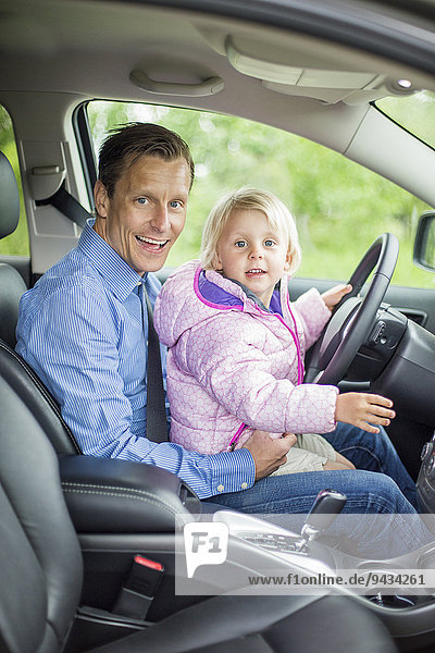 Porträt eines glücklichen Vaters und einer glücklichen Tochter im Auto