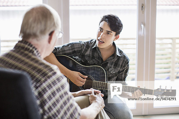 Enkel singen und Gitarre spielen für Großvater zu Hause