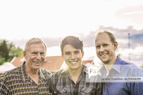 Porträt von drei Generationen männliche Familie lächelnd gegen den Himmel
