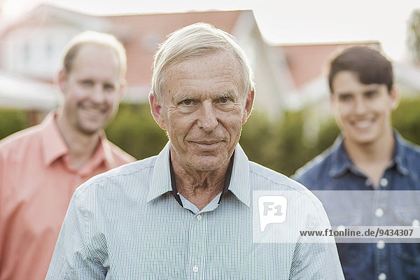 Porträt eines selbstbewussten älteren Mannes mit Sohn und Enkel im Hof stehend