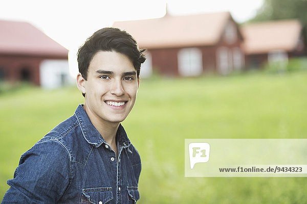 Porträt eines selbstbewussten jungen Mannes  der im Hof lächelt.