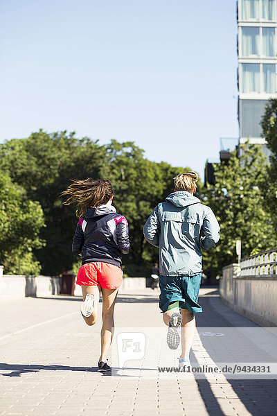 Full length rear view of multi-ethnic couple jogging on bridge