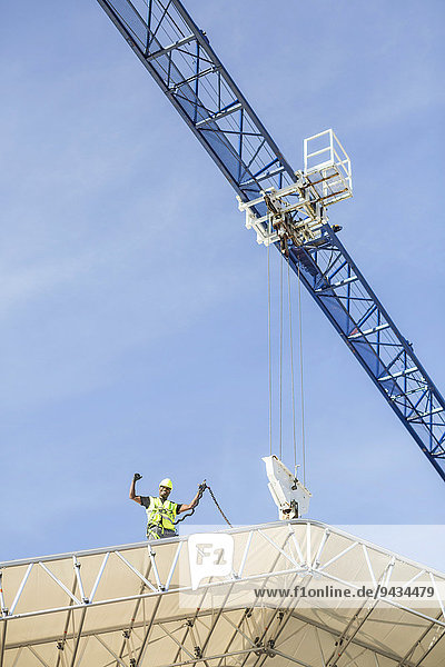 Niederwinkelansicht des erfolgreichen Arbeiters auf dem Dach auf der Baustelle