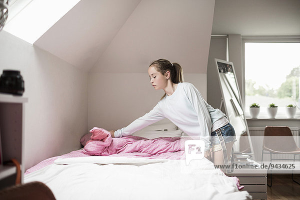 Girl making bed at home