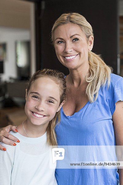 Porträt eines glücklichen Mädchens mit Mutter vor dem Haus stehend