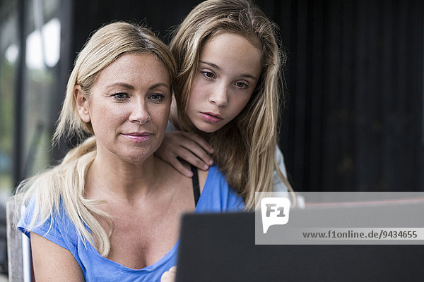 Mutter und Tochter mit Laptop auf dem Hof
