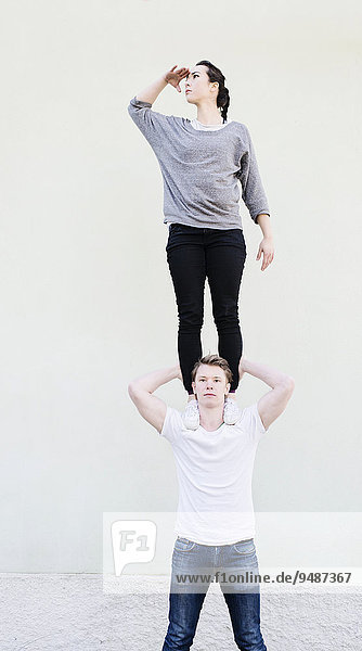 Woman standing on shoulders of man looking away  searching  conceptual image of teamwork  support and vision