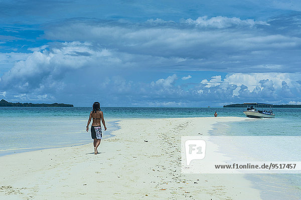 Tourist walking on a sand strip at low tide  Rock Islands  Palau  Oceania