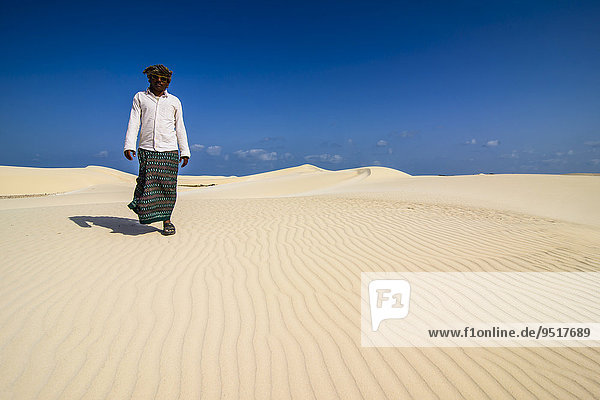 Local man walking through the sand dunes at the south coast of the island of Socotra  Yemen  Asia