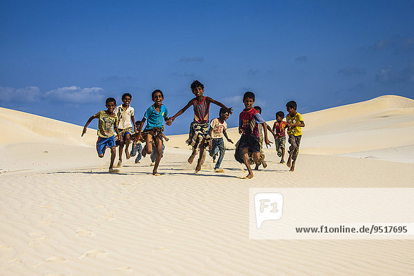 Young Socotrian boys running in the sand dunes at the south coast of the island of Socotra  Yemen  Asia