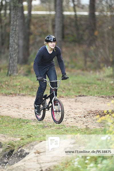 Teenager auf einem BMX-Rad im Wald