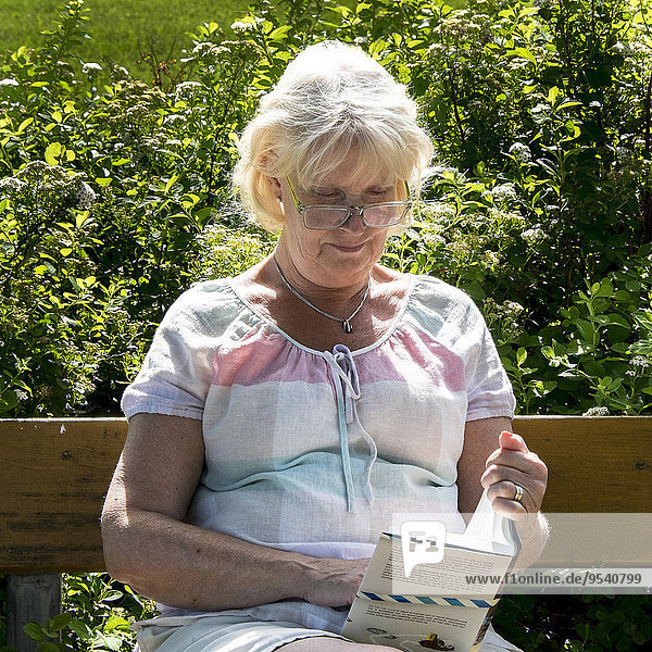 Senior Senioren Frau Buch Sitzbank Bank Taschenbuch vorlesen