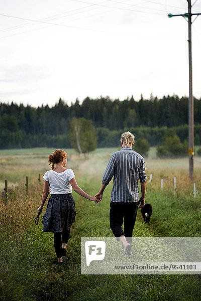 Young couple walking through grassy road