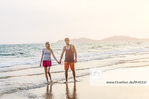 Young couple walking along beach at dusk