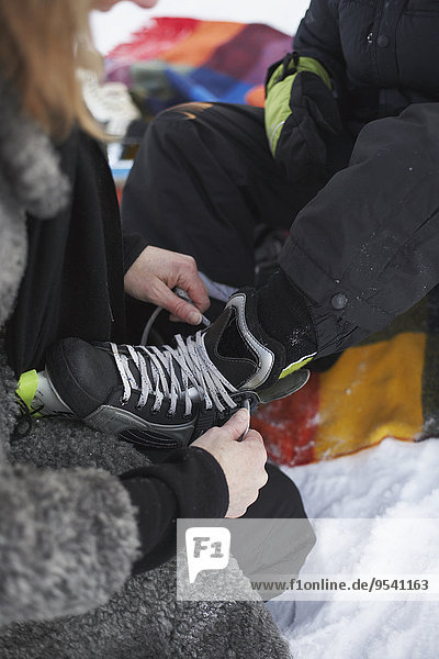 Mother tying childs ice skate