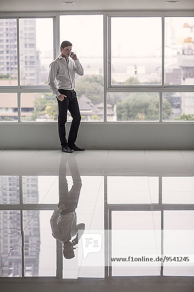 Businessman with cell phone in office building