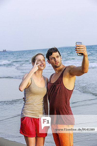 Young couple at beach taking selfie