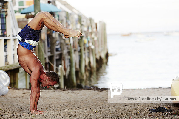 Man duing handstand on beach
