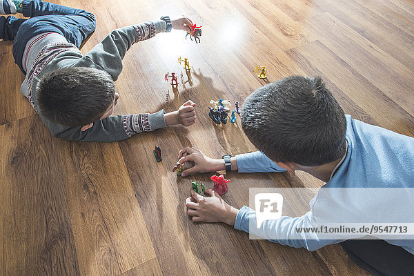 Zwei Jungen  die zu Hause mit Miniaturfiguren auf dem Boden spielen