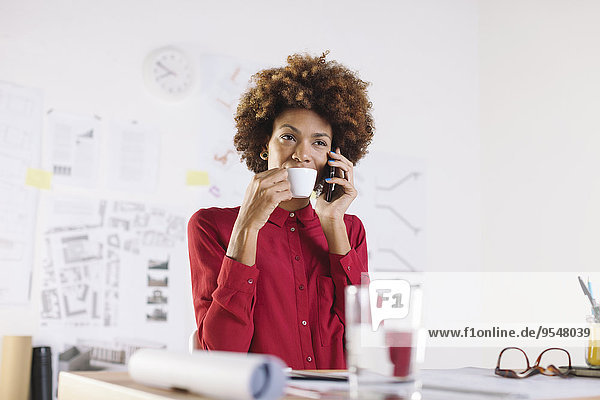Porträt einer jungen Architektin beim Telefonieren mit dem Smartphone beim Kaffeetrinken