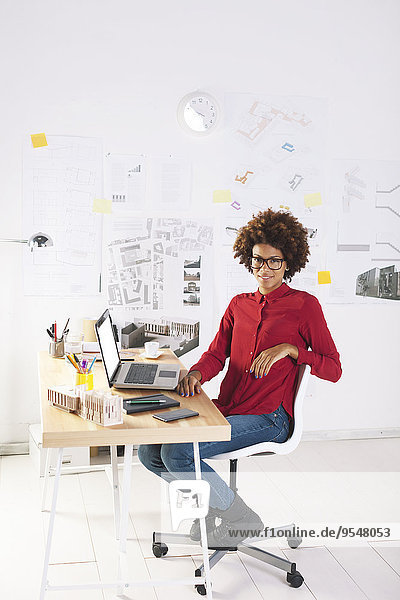 Young female architect with laptop at her desk