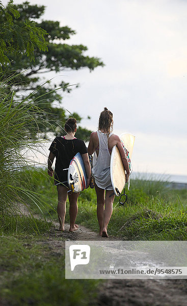 Indonesien  Bali  Canggu  zwei Frauen mit Surfbrettern auf dem Wanderweg