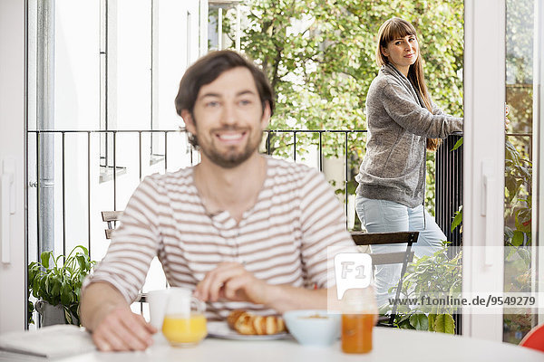 Mann beim Frühstück mit Frau auf dem Balkon
