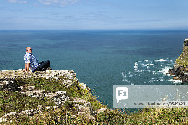 Vereinigtes Königreich  England  Cornwall  Tintagel  Tourist sitzend an der Steilküste