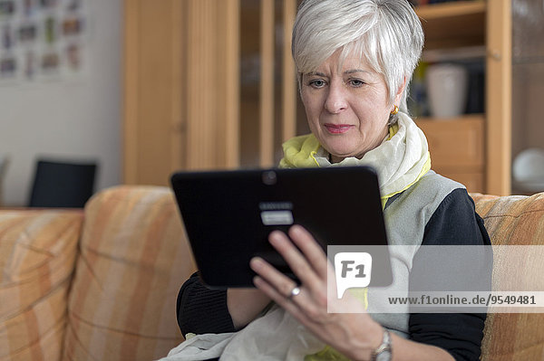 Seniorin mit digitalem Tablett auf dem Sofa