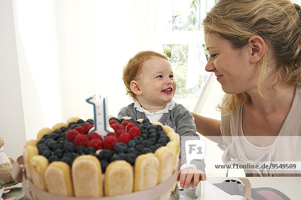 Mutter und Tochter feiern den ersten Geburtstag des kleinen Mädchens mit einem selbstgebackenen Kuchen.