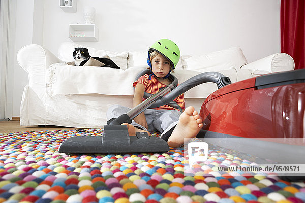 Exhausted boy in living room with cat and vacuum cleaner