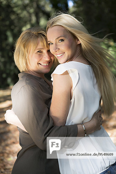 Mother and adult daughter embracing in park