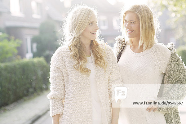 Portrait of two smiling blond women at backlight
