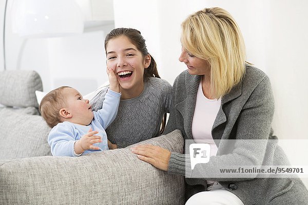 Mother sitting with daughter and baby boy on couch  smiling